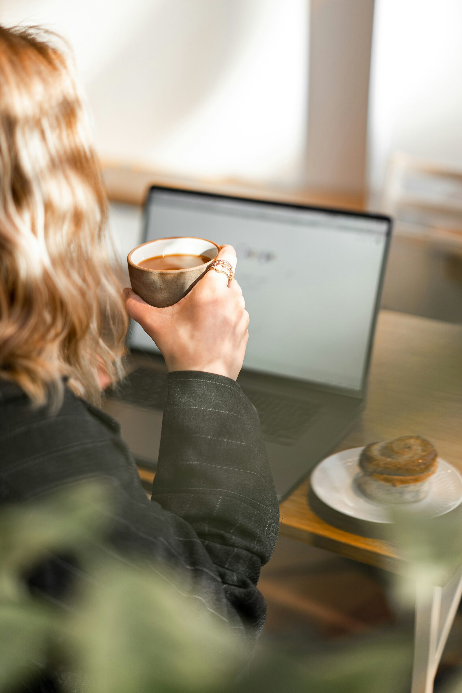 Someone sipping coffee in front of an open laptop